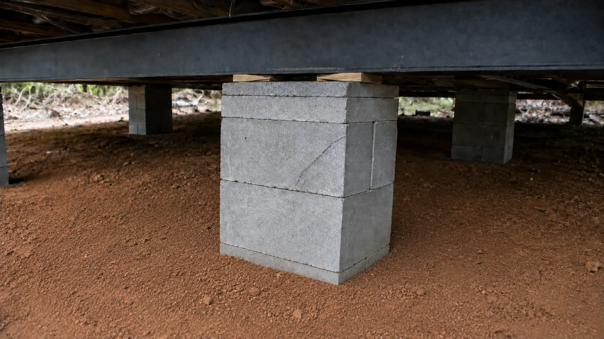 A block pier under a manufactured home frame with a visible crack through one block and the blocks set out of line with each other.